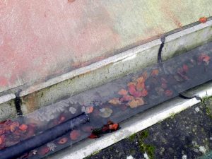 Unbekannte Chemikalie auf Betonboden und in einer wassergefüllten Rinne, Absaugschlauch.