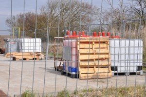 Diverse Gebinde mit Chemikalien auf einem Betriebsplatz der Öl- und Gasindustrie in Deutschland: Eventuelle Gefahrstoff-Hinweise sind vor den Blicken der interessierten Öffentlichkeit verborgen.